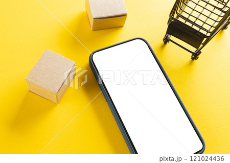 Smartphone with copy space and trolley with boxes on yellow background Smartphone with copy space and trolley with boxes on yellow background 121024436