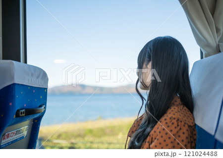 バスに乗って窓の外を眺める若い女性 121024488