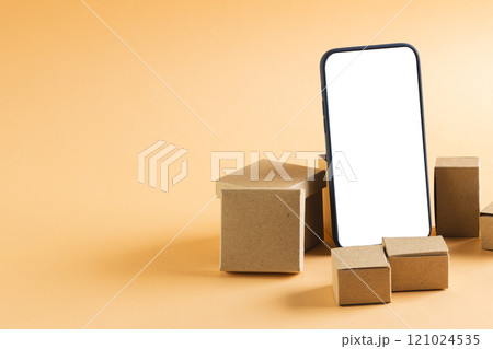 Smartphone with blank screen and cardboard boxes with copy space on yellow background Smartphone with blank screen and cardboard boxes with copy space on yellow background 121024535