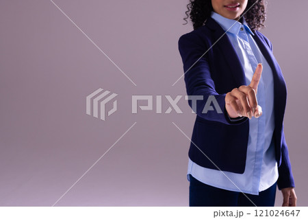 Biracial businesswoman pointing with copy space on grey background Biracial businesswoman pointing with copy space on grey background 121024647
