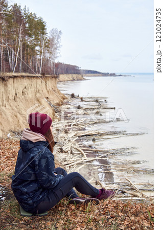 Woman sits on a cliff above coast and admires nature, enjoy solitude. traveling 121024735