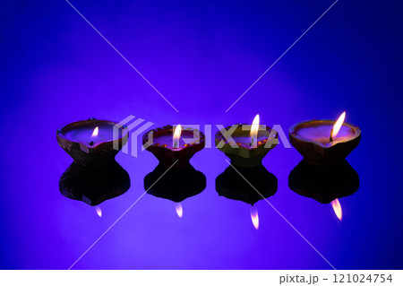 Close up of four diwali candles with copy space on purple background Close up of four diwali candles with copy space on purple background 121024754