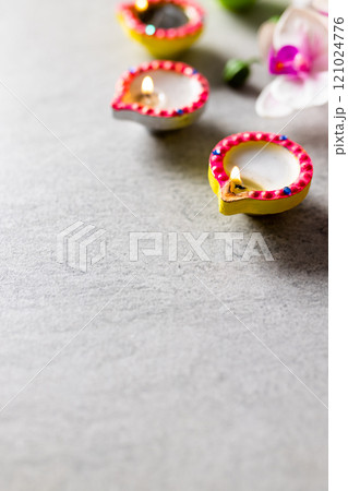 Close up of three diwali candles and flowers with copy space on grey background Close up of three diwali candles and flowers with copy space on grey background 121024776