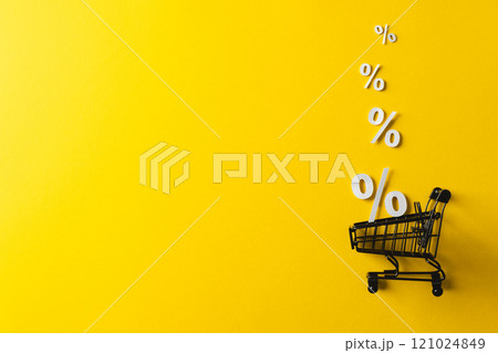 Shopping trolley and white percent signs with copy space on yellow background Shopping trolley and white percent signs with copy space on yellow background 121024849