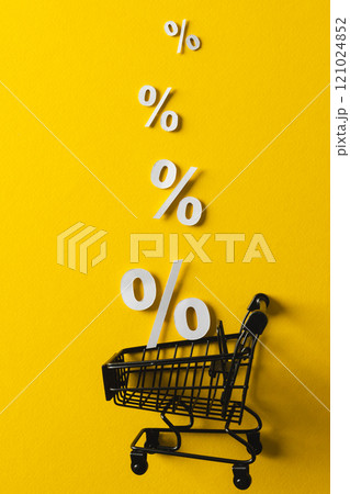 Shopping trolley and white percent signs with copy space on yellow background Shopping trolley and white percent signs with copy space on yellow background 121024852