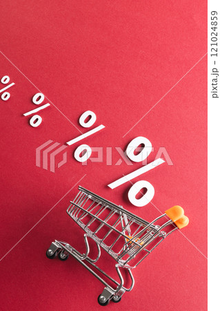 Shopping trolley and white percent signs with copy space on red background Shopping trolley and white percent signs with copy space on red background 121024859