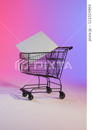 Vertical image of shopping trolley with blank canvas and copy space over neon purple background 121024964