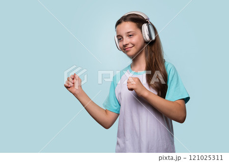 Girl dancing to music with headphones, enjoying the rhythm. 121025311