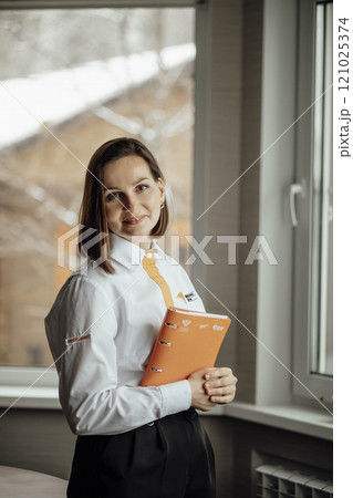 professional woman standing near a window, exuding confidence and focus, natural light and create a calm atmosphere 121025374