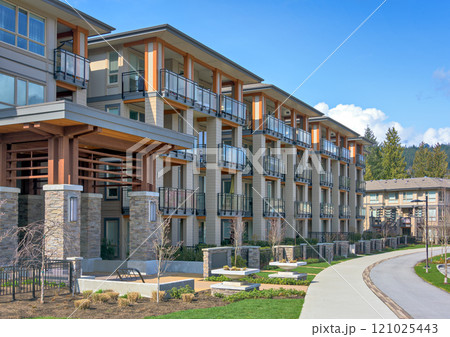 New residential apartment building with walkway and bike route in front on sunny day in British Columbia, Canada 121025443