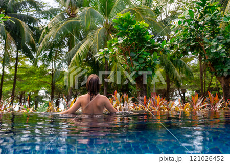 Enjoy a delightful experience of relaxing in a tropical pool surrounded by swaying palm trees Enjoy a delightful experience of relaxing in a tropical pool surrounded by swaying palm trees 121026452