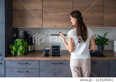 Young woman with healthy diet plan for weight loss, delivery of daily ready meal menu. Food ordered with mobile phone app. Balanced portion with dish. Pre-cooking. 121026881