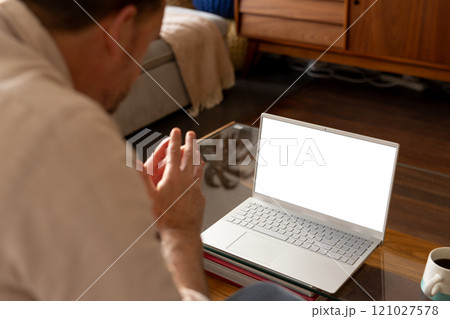 senior man video conferencing on laptop at home, engaging in virtual meeting, copy space 121027578