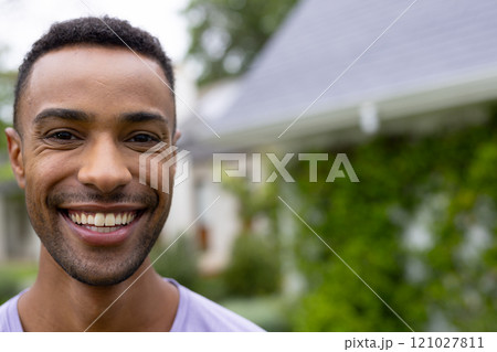 Smiling young african american man enjoying sunny day outdoors in front of house, copy space Smiling young african american man enjoying sunny day outdoors in front of house, copy space 121027811