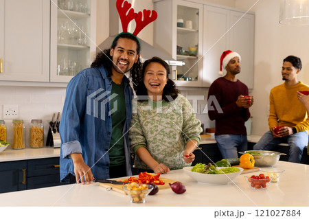 Multiracial friends celebrating christmas in kitchen, preparing food at home Multiracial friends celebrating christmas in kitchen, preparing food at home 121027884