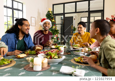 Multiracial friends enjoying festive christmas meal together, at home Multiracial friends enjoying festive christmas meal together, at home 121027954