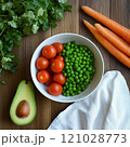 Fresh vegetables on wooden table with tomatoes, peas, carrots, avocado, and cilantro 121028773