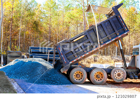 Dump truck is releasing large pile of gravel onto ground at busy construction site. Dump truck is releasing large pile of gravel onto ground at busy construction site. 121029807