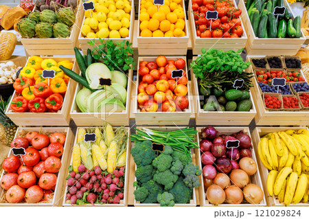 Colorful fruits, vegetables are arranged in crates, showcasing bounty of local market in bright sunlight. 121029824