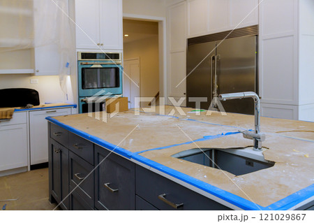 Renovation work is in progress in modern kitchen featuring exposed unfinished countertops appliances awaiting installation. 121029867