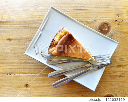 piece of cheesecake on a plate with forks on a wooden tabletop piece of cheesecake on a plate with forks on a wooden tabletop 121032169