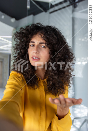 Confident woman gesturing while taking selfie with smartphone. Indoors setting adds modern and casual vibe to image. Confident woman gesturing while taking selfie with smartphone. Indoors setting adds modern and casual vibe to image. 121032358