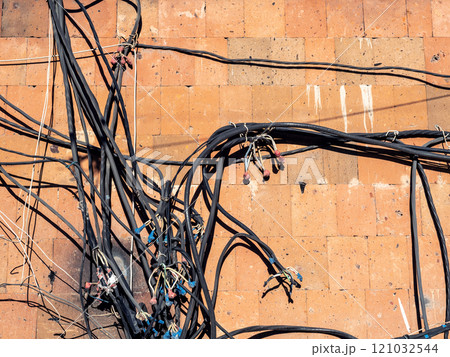 messy electrical cables and wires on outdoor wall 121032544