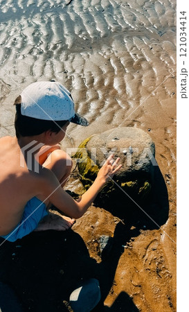 boy plays with stones on ribbed sand on the shore of the White Sea 121034414