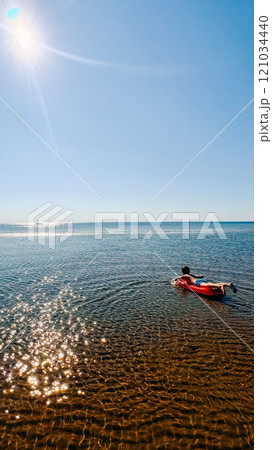 teenage boy swims on an inflatable mattress in the white sea 121034440