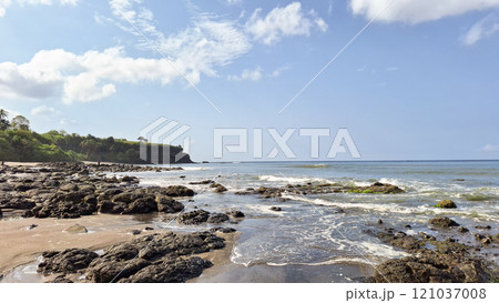Beautiful balinese landscape. Ocean beach. Ancient hinduism temple Tanah lot on the rock against cloudy sky. Bali Island, Indonesia 121037008
