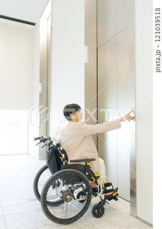 エレベーターに乗ろうとする車椅子ユーザー 121039518