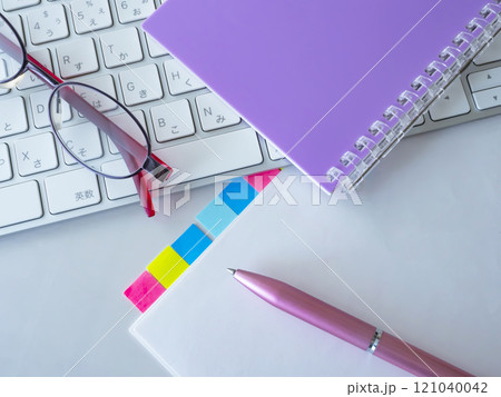 テーブルに置かれた書類とキーボードと手帳とメガネ テーブルに置かれた書類とキーボードと手帳とメガネ 121040042