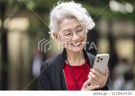 スマートフォンを持った笑顔のシニア女性 121042410