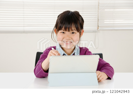 タブレット端末を操作して笑顔の小学生の女の子。 121042943
