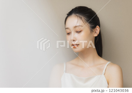 顔に手を当てて微笑む女性 121043036