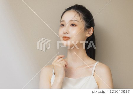 顔に手を当てて微笑む女性 121043037