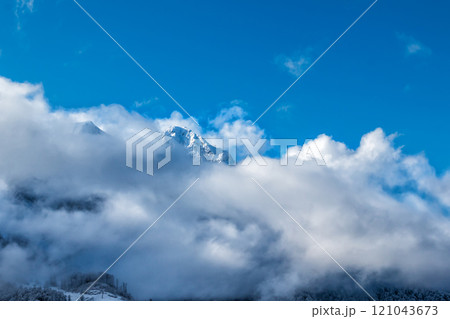 Mountain peaks looking out from under the clouds 121043673