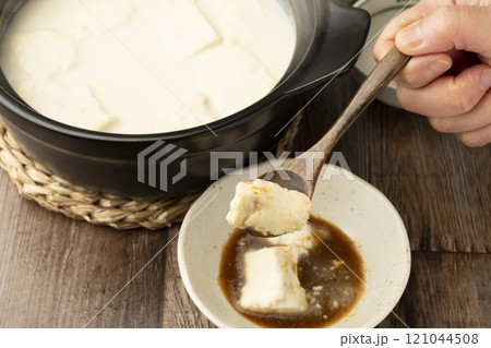 温泉豆腐 湯豆腐 土鍋で煮た豆腐をスプーンで持ち上げる 温泉豆腐 湯豆腐 土鍋で煮た豆腐をスプーンで持ち上げる 121044508