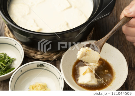 温泉豆腐 湯豆腐 土鍋で煮た豆腐をスプーンで持ち上げる 温泉豆腐 湯豆腐 土鍋で煮た豆腐をスプーンで持ち上げる 121044509