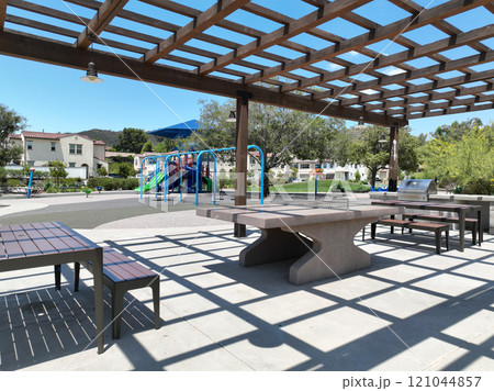 Covered gathering area in city park with green wood picnic tables Covered gathering area in city park with green wood picnic tables 121044857