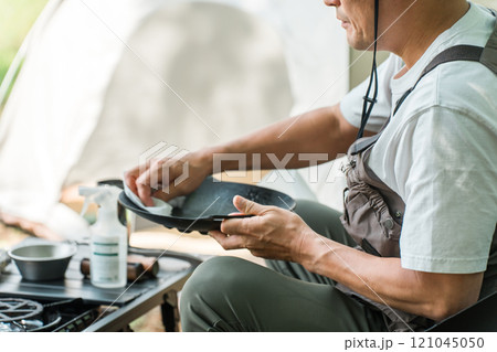 ソロキャンプで後片付けする男性キャンパー 121045050
