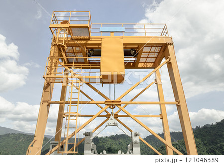 View of Yellow gantry overhead crane control watergate and water in the dam between the hills. View of Yellow gantry overhead crane control watergate and water in the dam between the hills. 121046389