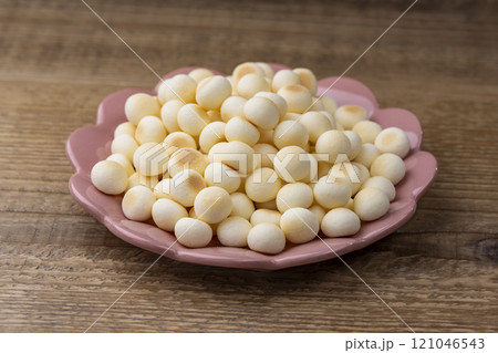 木目のテーブルに置かれたピンク皿とたっぷりのたまごボーロ 121046543