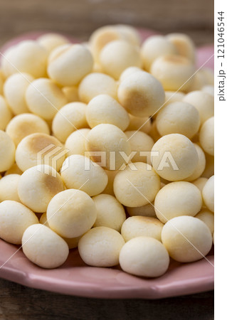 木目のテーブルに置かれたピンク皿とたっぷりのたまごボーロ 121046544