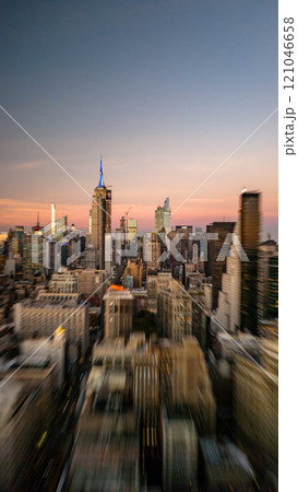The Empire State Building towers over Midtown Manhattan in New York City skyline at sunset, capturing the city's energetic atmosphere with a dynamic zoom effect 121046658