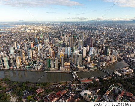 Aerial view of Manila, Philippines, showcasing modern skyscrapers and crowded residential areas reflecting in Pasig River, creating an iconic cityscape of an Asian metropolis 121046665