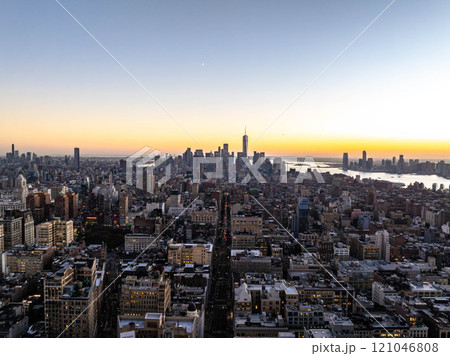 Glowing sunset hues light up the cityscape of Manhattan New York City, showcasing the iconic one world trade center in the background and Flatiron District in the foreground 121046808