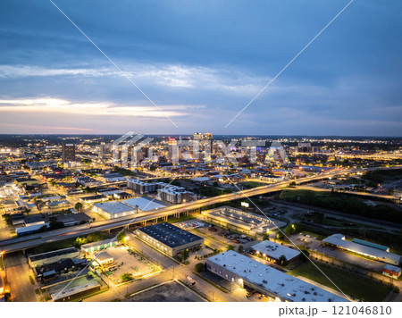 Aerial view of Birmingham, Alabama at dusk, showcasing the city's illuminated skyline and highway traffic, creating an urban nightscape with dramatic cloudy sky Aerial view of Birmingham, Alabama at dusk, showcasing the city's illuminated skyline and highway traffic, creating an urban nightscape with dramatic cloudy sky 121046810