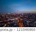 Berlin TV tower, a striking landmark, looms over the cityscape at dusk, illuminating the urban skyline with a warm glow from an aerial view 121046860