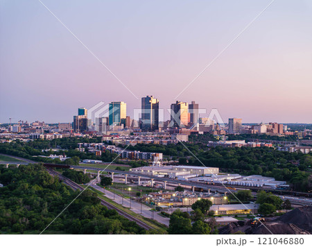 Aerial view of Fort Worth, Texas at dusk, vibrant cityscape, prominent skyscrapers, modern low residential buildings, active rail yard, and lush greenery Aerial view of Fort Worth, Texas at dusk, vibrant cityscape, prominent skyscrapers, modern low residential buildings, active rail yard, and lush greenery 121046880